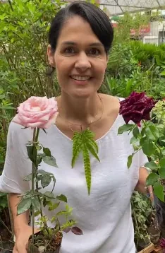 Aluna no canteiro ao lado de uma rosa grande e bem formada
